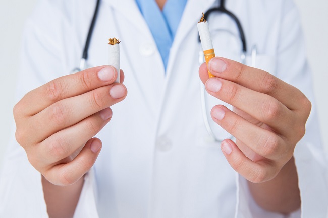 Doctor breaking cigarette on white background